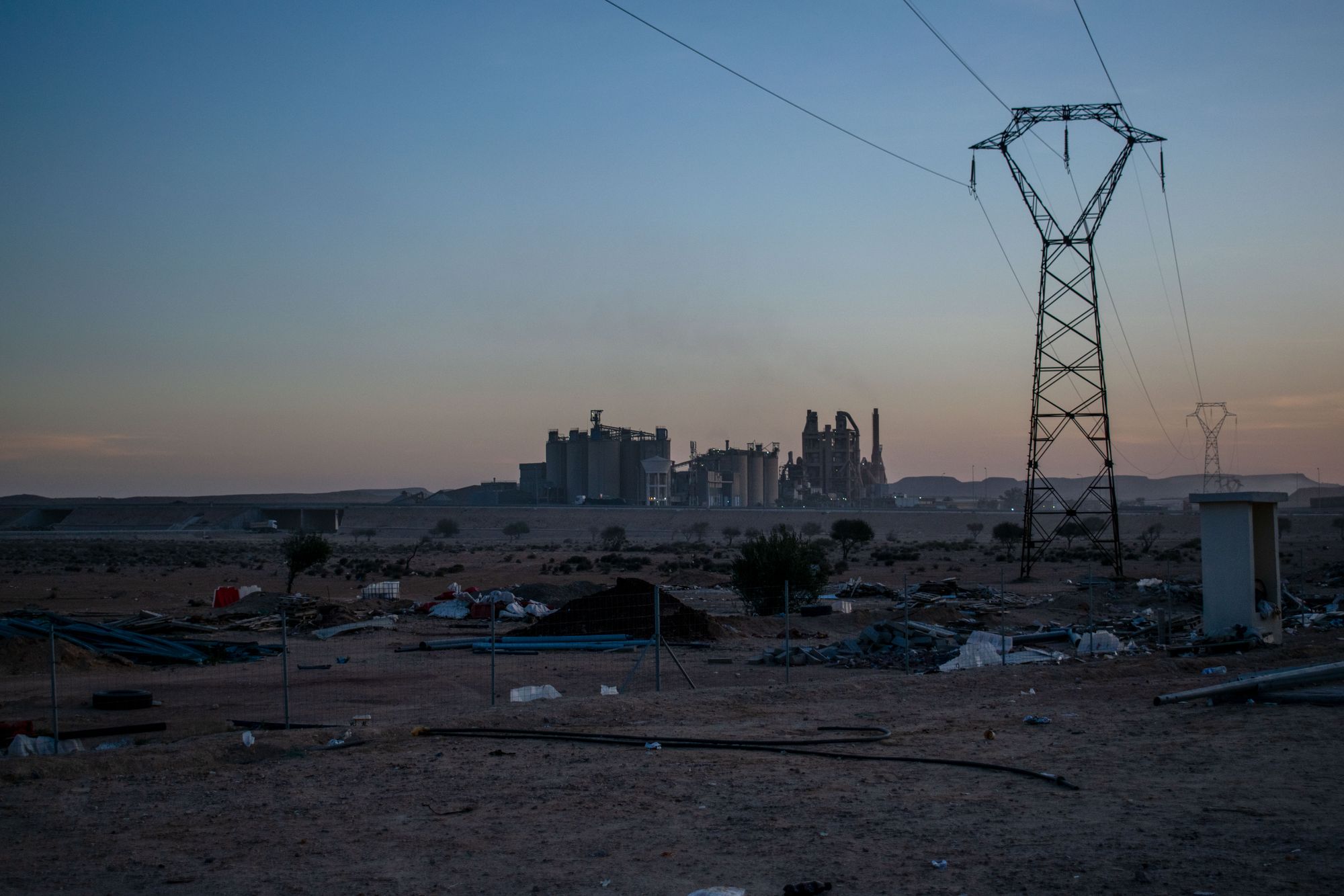 Onlooking a powerplant with a foreground of litter and debris. Behind me, everyone else is stretching their legs after a quick bathroom break